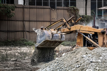 bulldozer at the construction site pours rubble. Toned.