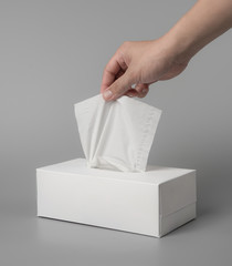female hand pulling white facial tissue on grey background for print design and mock up