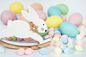 Wall Mural - Colorful Assorted sizes Pastel Easter Eggs. Happy Easter card with a vintage wooden bunny with copy space