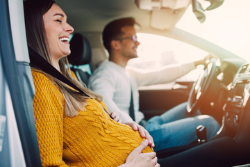 Husband and his pregnant wife driving in car.