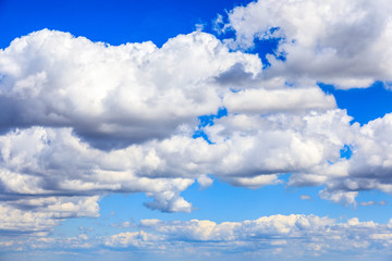 white cumulus summer clouds against a deep blue sky.