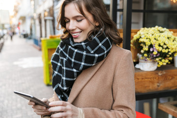 Wall Mural - Beautiful happy young woman using tablet computer outdoors walking by street.