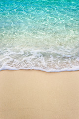 Soft blue ocean wave on clean sandy beach