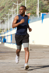 Wall Mural - Full length fit young black man running outdoors
