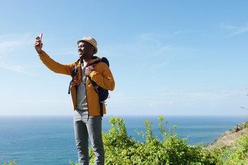 happy male traveler taking selfie in nature by sea