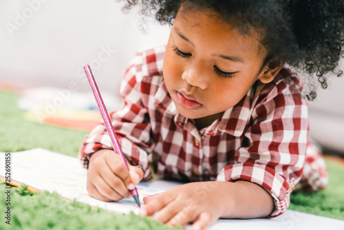 Fotografía Cute young African American kid girl drawing or painting with colored pencil