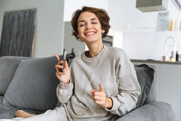 Canvas Print - Happy young woman sitting on a couch at home