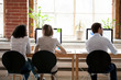 © fizkes - Women and man sitting in shared office rear back view