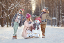 Mom And Children In The Winter Forest Play Snowballs And Make A Snowman. Walking In The Winter Holidays.