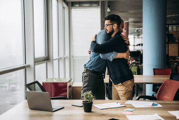 Poster - Two business colleagues hug and congratulate each other with success in their office