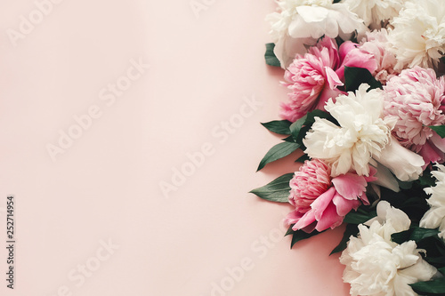 Fotomural Stylish pink and white peonies border on pink paper flat lay with space for text