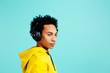 © Carlos David - Portrait of a young man with headphones looking to the side,  isolated on blue background
