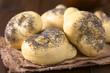 Homemade poppy seed bread rolls on fabric on dark wood, photographed with natural light (Selective Focus, Focus one third into the first roll)