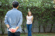 © NT_studio - Young asian man holding behind back gift box surprise girlfriend excited in the garden with happy, anniversary day of couple, romantic love together with celebration, family and lifestyle concept.
