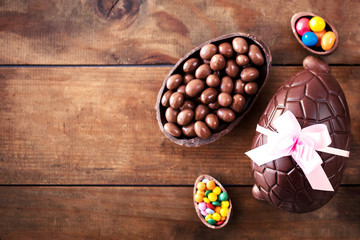 Chocolate Easter eggs on wooden background with ribbon bow and candies. Happy Easter!.