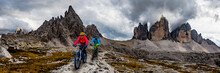 Cycling Woman And Man Riding On Bikes In Dolomites Mountains Andscape. Couple Cycling MTB Enduro Trail Track. Outdoor Sport Activity.