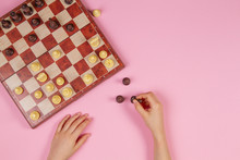 Kid Hands Over A Chessboard Playing Chess Game On Pink Background, Top View