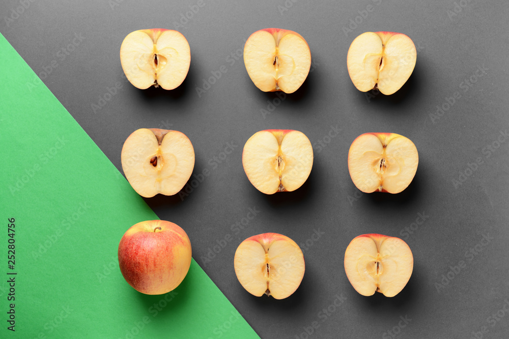 One whole apple among cut ones on grey background. Uniqueness concept