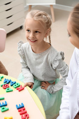 Sticker - Little girl with speech therapist composing words of letters in office