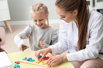 Canvas Print - Little girl with speech therapist composing words of letters in office