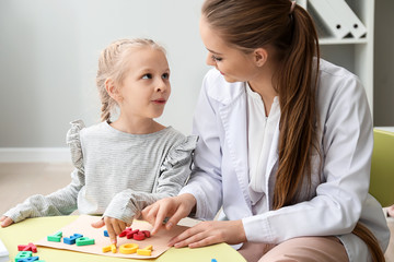 Wall Mural - Little girl with speech therapist composing words of letters in office