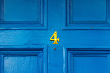 House Number 4 In Bronze On A Blue Painted Wooden Door