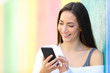 © Antonioguillem - Happy woman is browsing smart phone beside a colorful wall