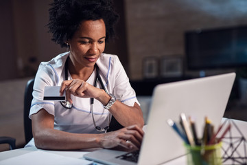 Wall Mural - Smiling African American female nurse shopping online.