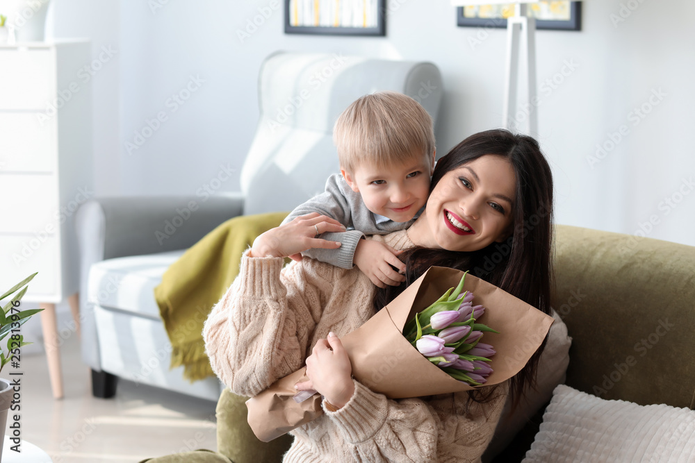 Little boy greeting his mother with 8 March at home