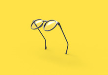 Studio Shot Of Flying Black Glasses On Yellow Background