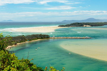 Top view of the Nambucca Heads lagoon with people doing stand-up paddle in the turquoise water. Australia.