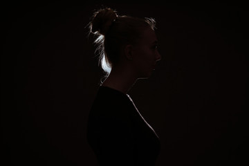 profle view of woman hiding in the dark to preserve anonymity - backlit contour with rim light