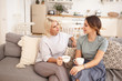 © shurkin_son - People, lifestyle, family and relationships concept. Pretty girl visiting her middle aged mother. Beautiful blonde woman speaking to her young daughter, sitting in living room with mugs, drinking tea
