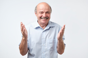 Wall Mural - Happy bald senior man bragging about the big size of something