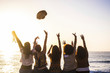 © simona - Summer and happiness for travel and freindship concept with group of happy girls viewed from rear enjoying and celebrating the sunset and the sea together launching hat and giving up