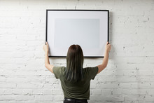 Back View Of Woman Holding Blank Black Frame In Hands