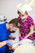 © F8  \ Suport Ukraine - Male dentist and female assistant checking up patient teeth with dental tools microscope, mirror and probe at dental clinic office. Medicine, dentistry and health care concept. Dental equipment