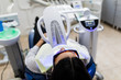 © F8  \ Suport Ukraine - Patient with safety protective glasses and cheek retractor on. Laser light lamp turn on as a procedure of Professional Teeth Whitening. Women's Cosmetic and Aesthetic Dental Care Health Concept.