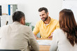 selective focus of advisor sitting at table and smiling to investors in office