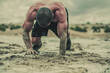 © Paul - Closeup of strong athletic, muscular man crawling in wet muddy puddle in the rain in an extreme competitive sport
