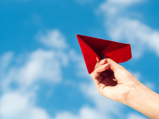 Woman Hand holding red paper rocket with blue sky background. freedom concept