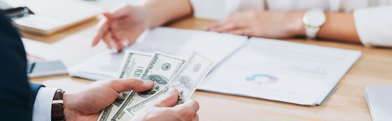 selective focus of man holding dollar banknotes at office