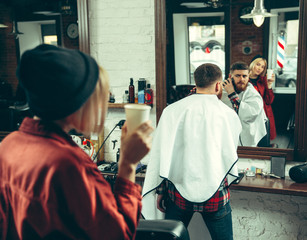 Wall Mural - Client during beard shaving in barbershop. Female barber at salon. Gender equality. Woman in the male profession.