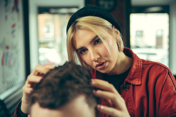 Wall Mural - Client during beard shaving in barbershop. Female barber at salon. Gender equality. Woman in the male profession.