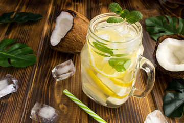 Wall Mural - Cold lemonade with coconut,lemon and mint on the  brown wooden background