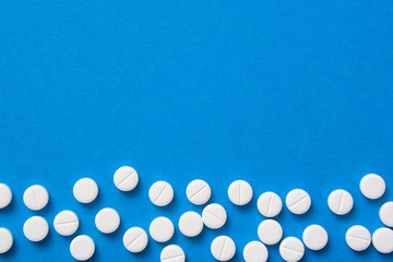 White pills on blue background top view for text