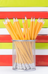 stationery cup with pencils stands on the background of colored books