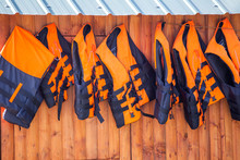 Orange Life Jackets Hanging On A Wooden Wall