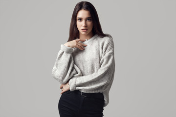 Beautiful brunette woman in sweater posing in studio