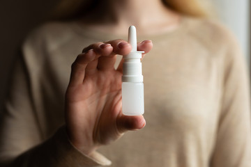 The girl uses spray on a dark background. Medicine and treatment